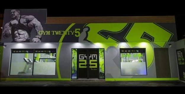 The lime-green GYM TWENTY5 storefront at night
