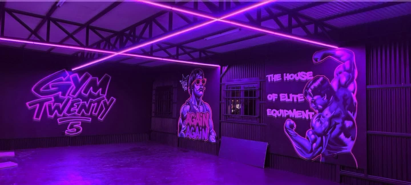 The UV room: neon light beams over a GYM TWENTY 5 mural and an Again Again character